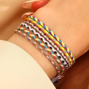 Close-up of bohemian colorful woven cord bracelets in a stack on a person's wrist