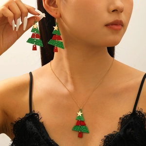 Close-up of festive Christmas tree pendant necklace and matching drop earrings on a model