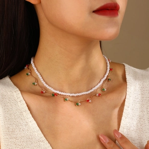 Détail d'un collier double épaisseur avec perles blanches et pendentifs rouges et verts