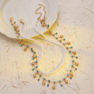 Détail de chaîne dorée avec strass bleus, perles et pendentifs en forme de cœur