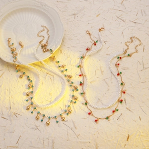 Détail du collier de perles avec fausses perles, pendentifs cœur dorés et billes colorées