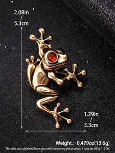 Macro shot of gold frog brooch with red gem eyes and precise dimensions 5.3cm x 3.3cm