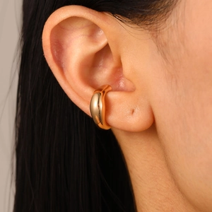 Vista detallada de un ear cuff de oro pulido puesto en la oreja con diseño minimalista