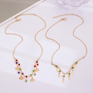 Détail de colliers dorés superposés avec charms mauvais œil et pendentifs goutte