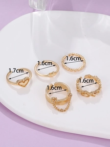 Detailansicht eines 5er-Sets goldener Ringe mit Herz- und Kettenmotiven aus Legierung