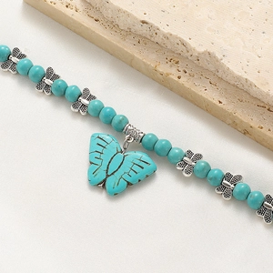 Close-up of turquoise beaded necklace with silver butterfly spacers and large butterfly pendant