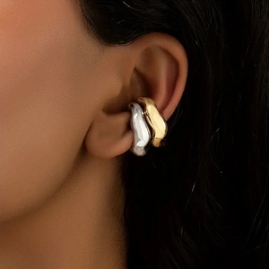 Primer plano de pendientes ear cuff de oro y plata con acabado pulido efecto metal líquido