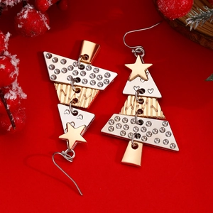 Close-up of golden and silver layered Christmas tree earrings on a festive red background