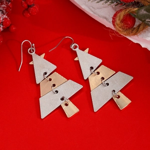 Detail of layered Christmas tree earrings with silver and gold metal textures on red