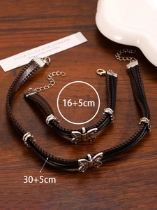 Butterfly charm jewelry set with woven cord choker and bracelet on a wooden table