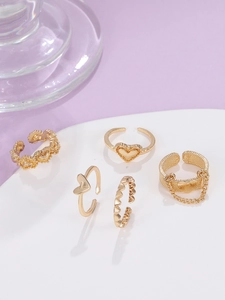 Detail von fünfteiligem Gold-Herz-Ring-Set mit verstellbaren Bändern auf weißem Tablett