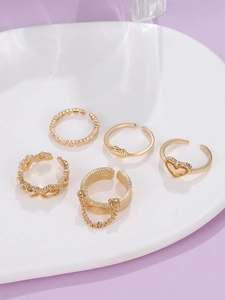 Detailansicht des fünfteiligen goldenen Ringsets mit Herz- und Kettenelementen