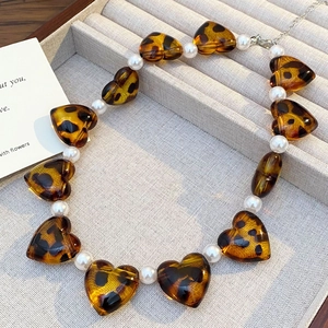 Detailed close-up of heart-shaped leopard resin beads and elegant white pearls necklace