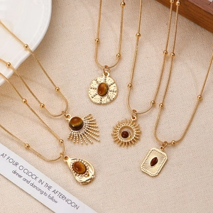Detailed view of four vintage gold necklaces with brown tiger eye stone pendants