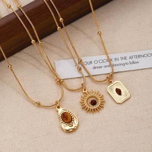 Detail of three vintage gold necklaces with teardrop, sunburst, and rectangle eye pendants