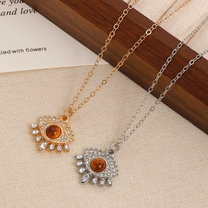 Close-up of eye-shaped pendants with tiger eye stone and crystals on natural fabric