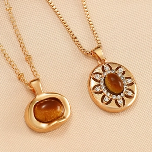 Macro detail of vintage gold pendant necklaces featuring brown tiger eye stones and diamonds
