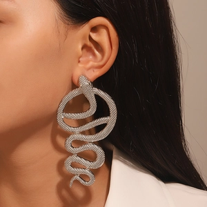 Close-up of a model wearing large silver snake-shaped earrings with textured finish