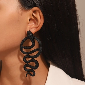 Detailed view of matte black snake-shaped earrings with textured skin on a model