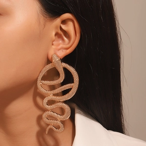 Detailed close-up of oversized rose gold snake earring with textured metal surface on model