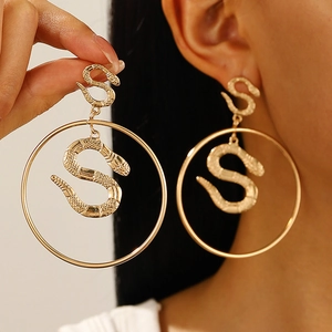 Macro shot of punk style golden snake earrings with textured scales on a large hoop