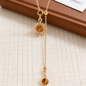 Detail of sunburst gold pendant with tiger eye stone and elegant double layered chain
