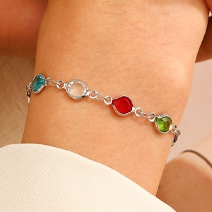 Gros plan détaillé d'un bracelet chaîne argenté avec pierres précieuses colorées au poignet