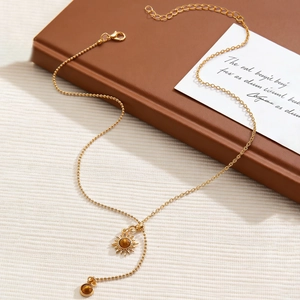 Detail of gold-plated Y-necklace with sun pendant and brown tiger eye stone