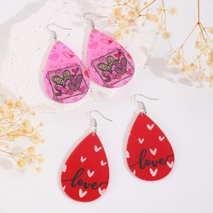Detail of teardrop earrings with pink heart patterns and red love lettering charms