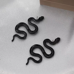 Macro shot of punk style black snake earrings with winding S-shape and glossy metal finish