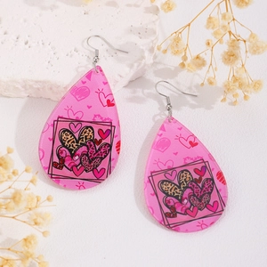 Gros plan détaillé des boucles d'oreilles cœur rose léopard sur fond de pierre blanche