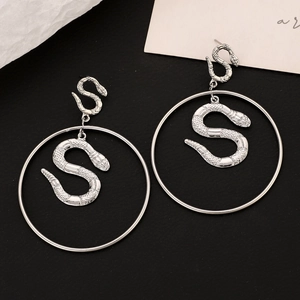 Macro shot of silver alloy punk snake earrings with textured scales and large rings