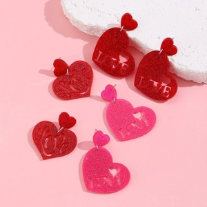 Detail of glitter resin heart drop earrings featuring a cutout LOVE letter design