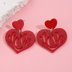 Detailed close-up of red glitter resin heart earrings with cutout Love design and metal pins