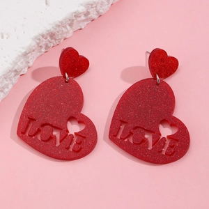 Close-up of red glitter heart earrings with LOVE cutout and silver metallic studs