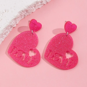 Close-up of pink glitter heart earrings featuring LOVE cutout text and resin texture