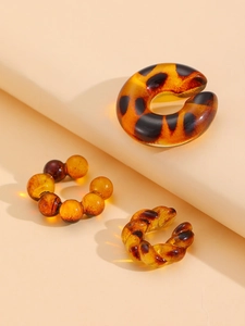 Detail of three vintage leopard print acrylic ear cuffs with amber textures on beige background