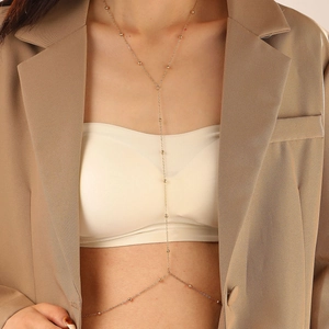 Chaîne de corps dorée minimaliste à perles en forme de Y portée avec un blazer chic