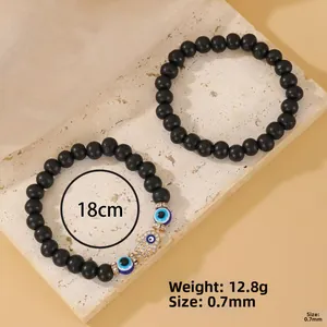 Detail of matte black beads with Fatima Hand and Evil Eye charms on elastic bracelet