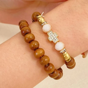Detail of beaded bracelet set featuring a diamond cross pendant and brown wooden beads
