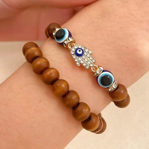 Close-up of wood bead bracelet set with Hamsa Hand pendant and Evil Eye accents