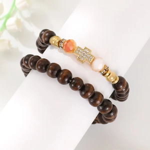 Two-piece wooden beaded bracelet set with rhinestone cross pendant on white stand