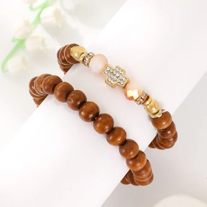Detail of wooden beaded stretch bracelets featuring a rhinestone cross charm and gold accents