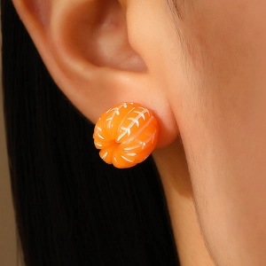 Macro shot of miniature 3D orange resin stud earrings showing realistic fruit texture