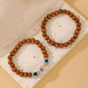 Detail of wooden bead bracelets with Hamsa Hand and Evil Eye charms on stone display