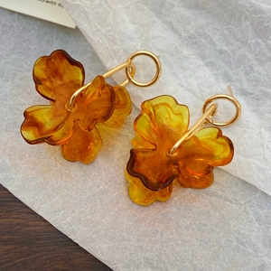 Detailed macro shot of amber resin flower petal earrings with gold metal rings