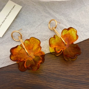 Close-up of amber resin flower dangle earrings with gold metal stems on a card