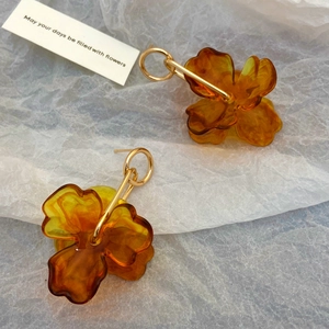 Close-up of amber flower drop earrings made of translucent resin with gold metal hoops