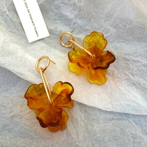 Detailed macro view of amber acrylic flower earrings with golden ring and metal accents