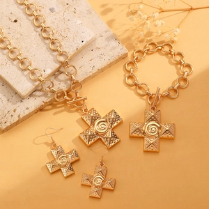 Dettaglio di set di gioielli vintage dorati con croci a spirale e chiusura OT
